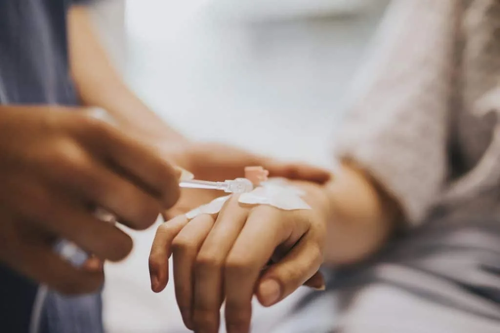 A clinician placing an IV cannula in a patient's hand