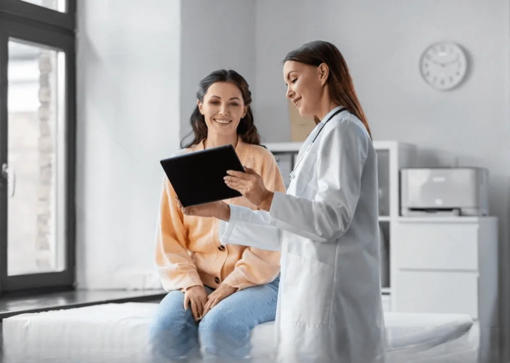 A clinician showing a tablet to a seated patient during a consultation