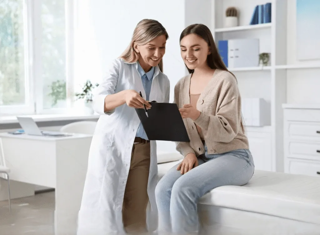 A clinician reviewing notes on a clipboard with a seated patient