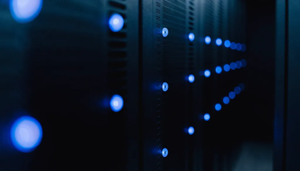 A row of server cabinet doors in a small equipment closet, cool blue indicator lights